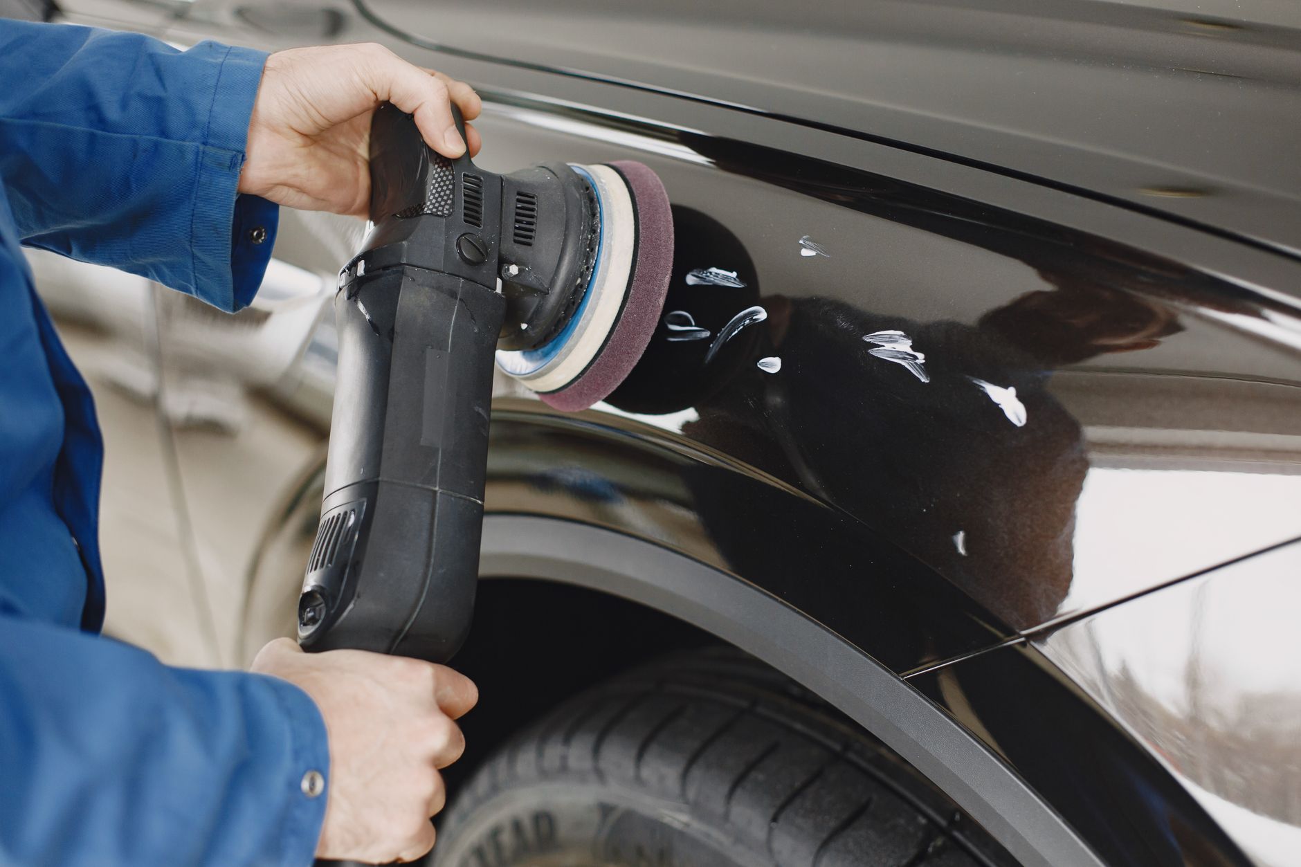 Detailer hands polishing a car with a buffer, craftsmanship close-up